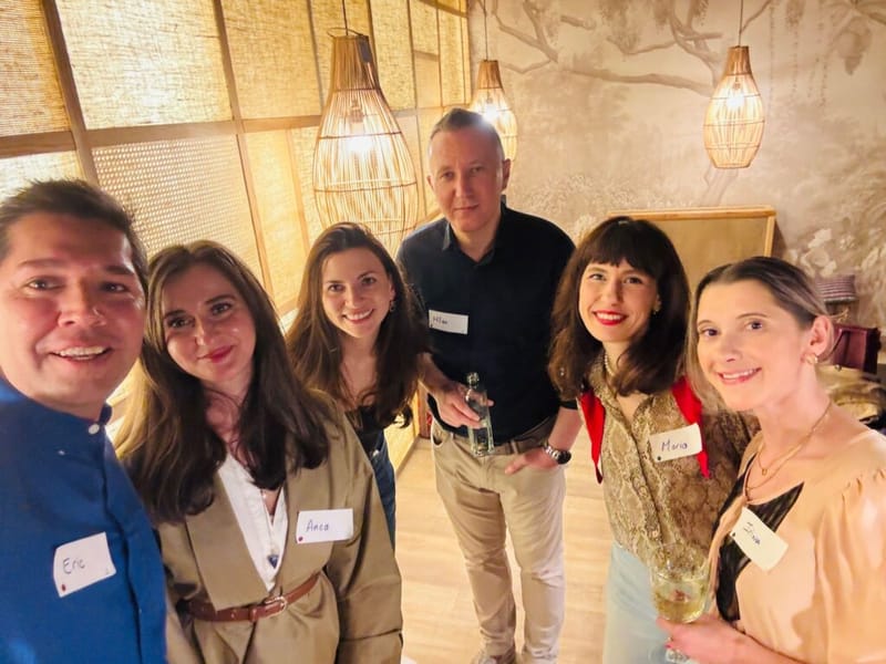 Eric Melchor taking a group selfie with five attendees at a 3rd Space Bucharest event, bamboo pendant lights overhead