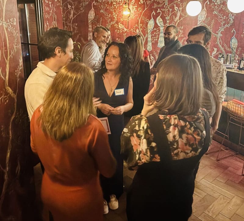 Attendees in conversation at a 3rd Space Bucharest networking event, standing in a warmly lit room with red floral wallpaper